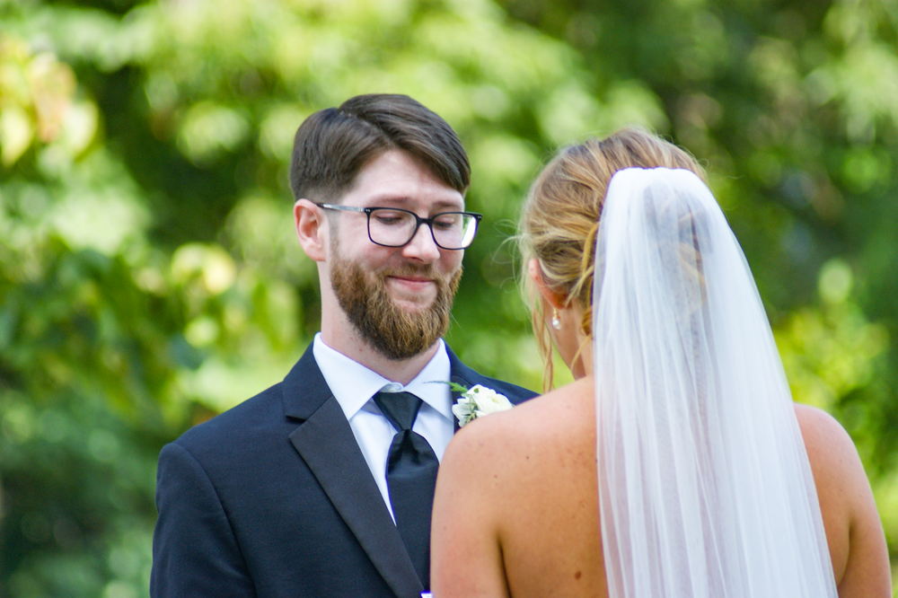 Wedding couple shares intimate moments in lush green garden setting.