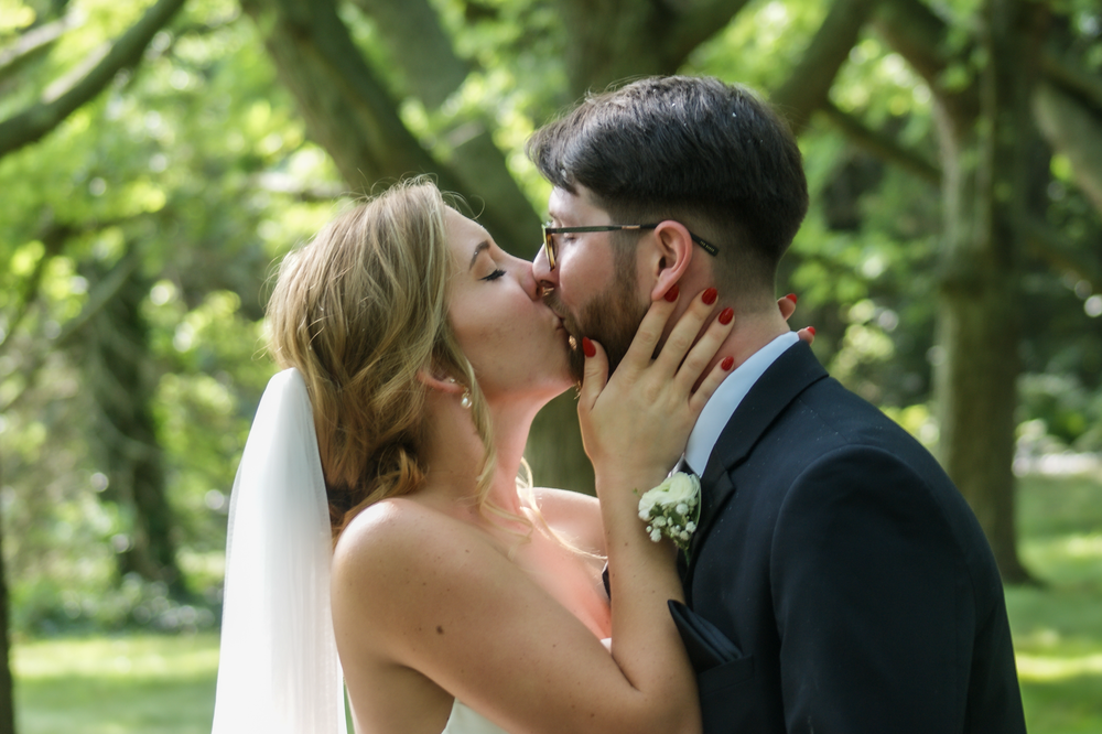 Wedding couple sharing intimate moments in a lush green garden setting.