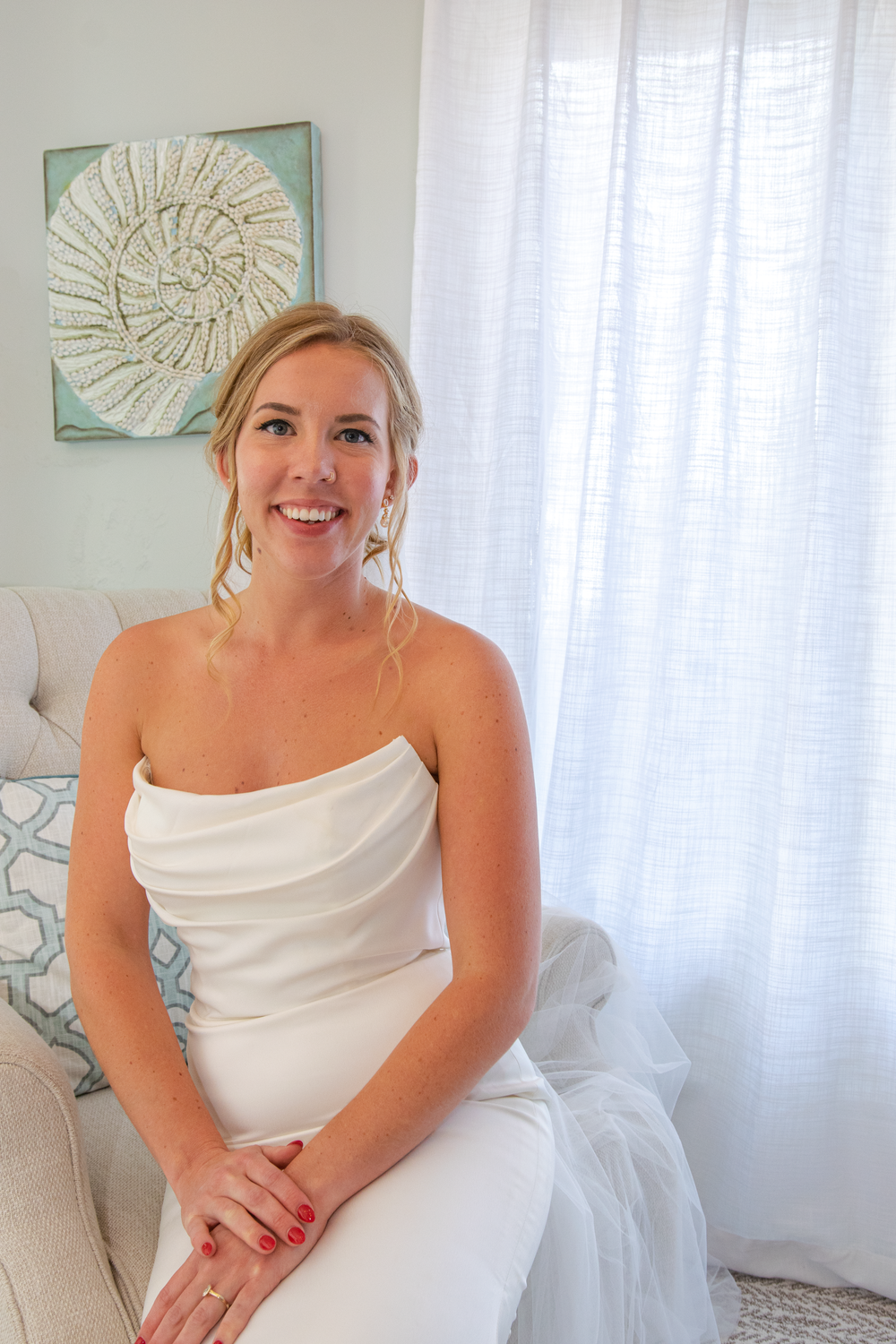 Bridal portraits in a bright white room with coastal-inspired wall art.