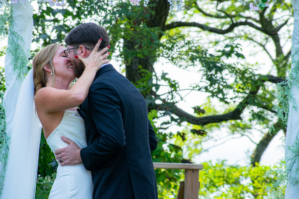 Wedding couple sharing romantic moments under green trees on their special day.
