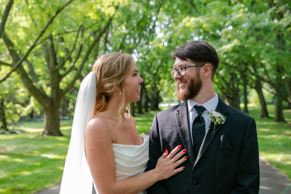 Wedding portraits taken on tree-lined path with natural green backdrop.