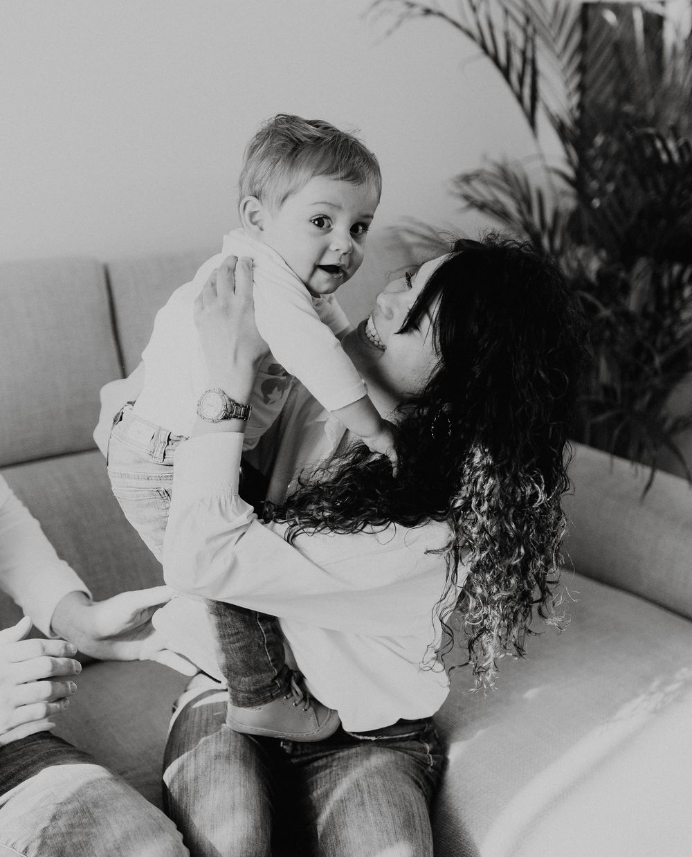 Black and white photograph showing a joyful moment with a baby sharing laughter while sitting on a couch.