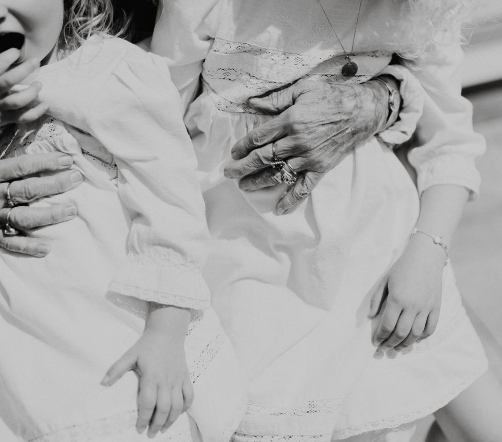 Une image en gros plan en noir et blanc montrant des mains de personnes âgées et de jeunes ensemble dans des vêtements blancs.
