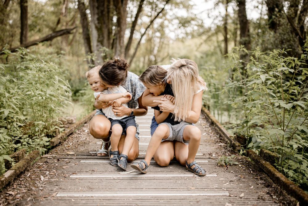 Famille assise ensemble sur une promenade en bois entourée d'une verdure luxuriante.