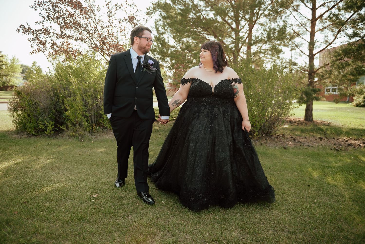 Newlywed couple embraces near serene lake with mountains in background on their wedding day.