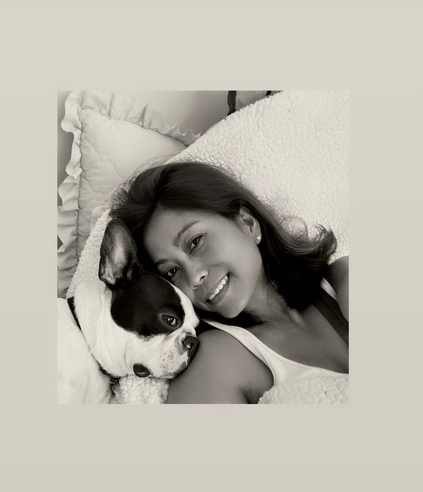 Black and white portrait showing intimate connection between dog and woman with white bedding.