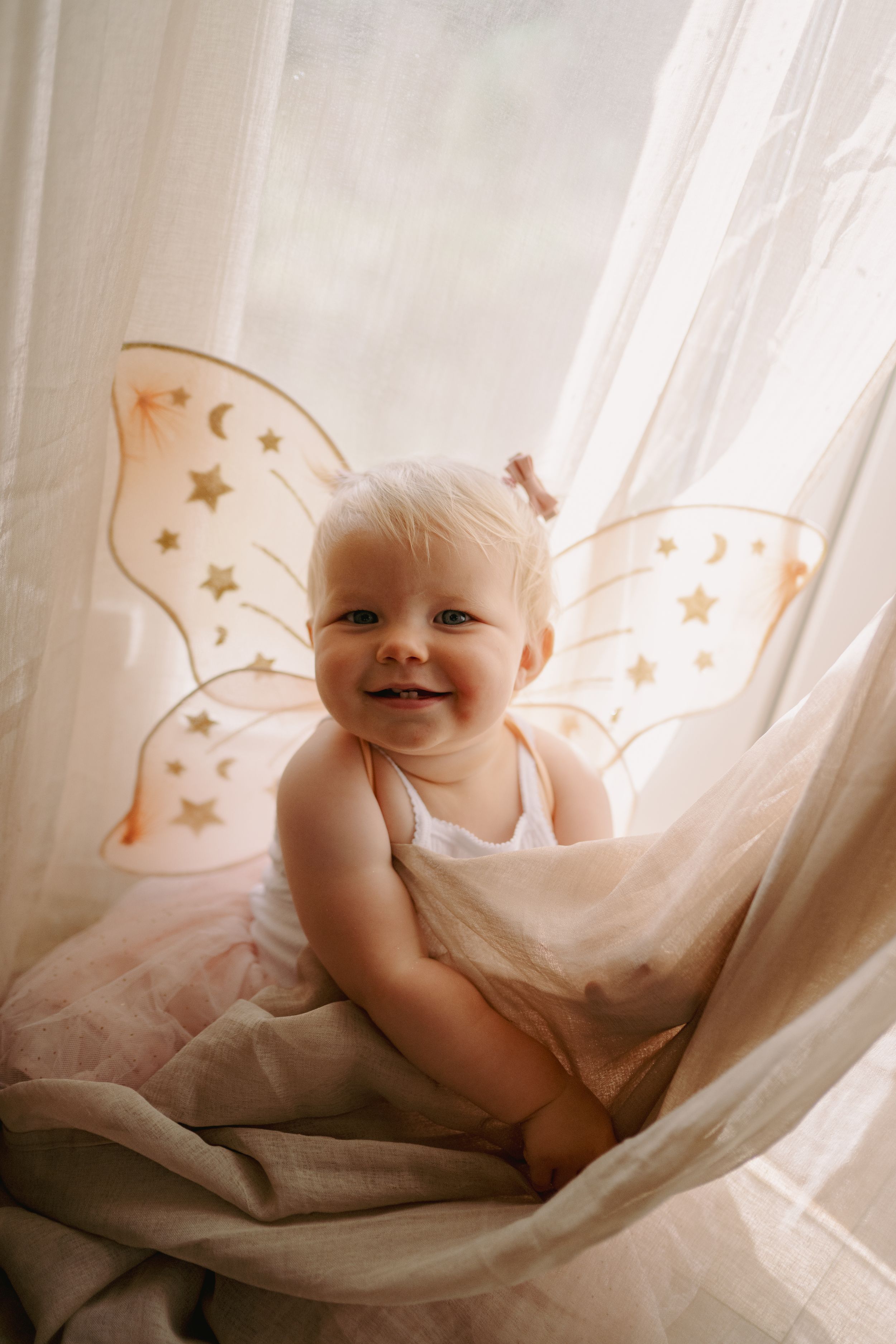 Sweet whimsical baby photography set featuring soft white fabric and delicate golden star decorations in natural light.