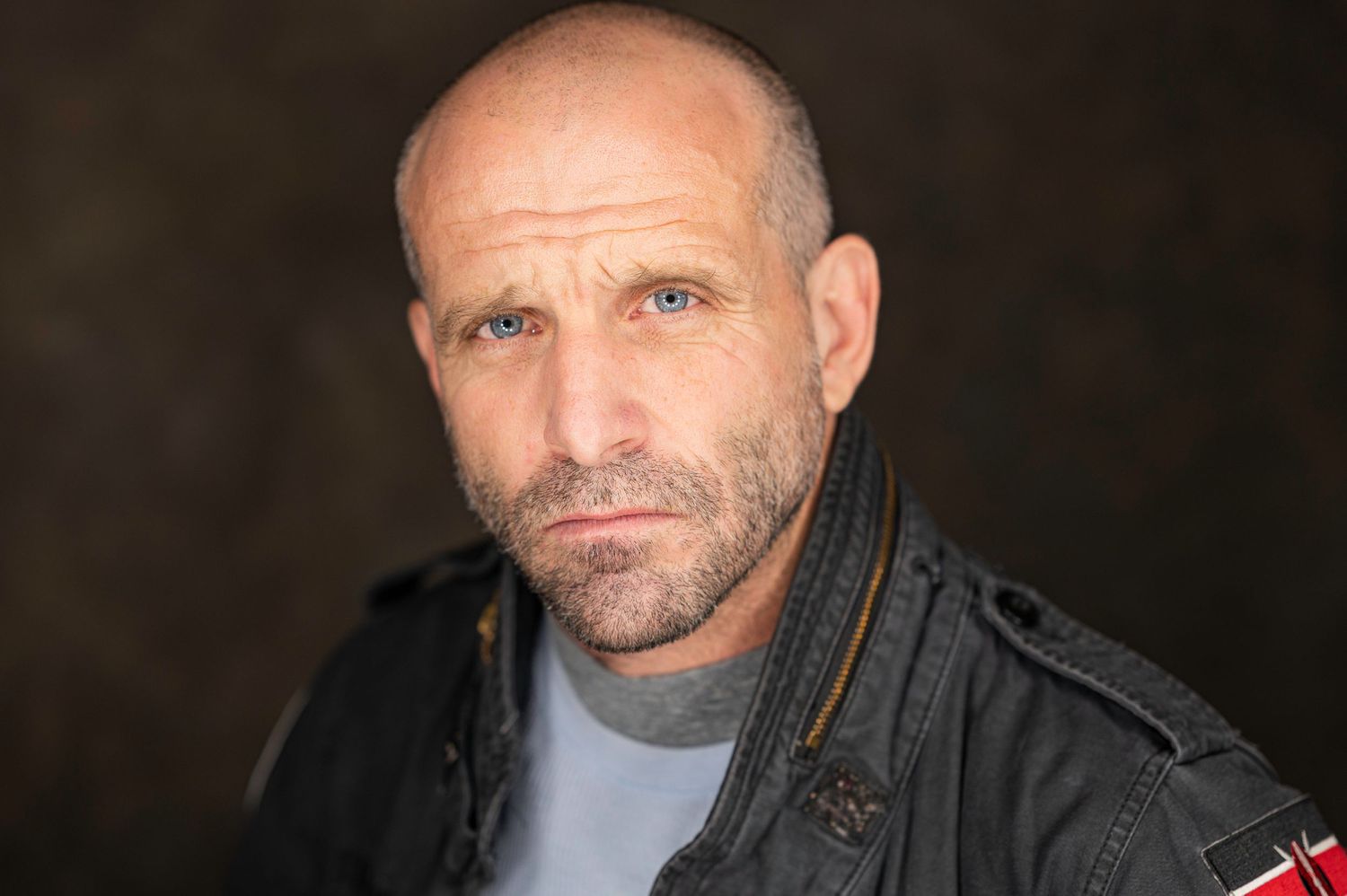 A dramatic portrait of a person in leather jacket against a dark background.