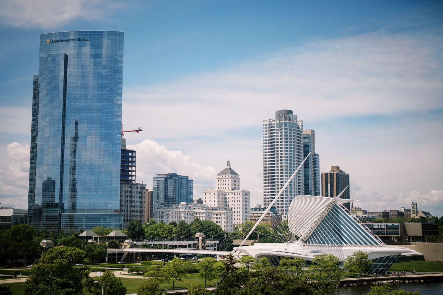 Modern skyline of downtown Milwaukee featuring glass skyscrapers and the iconic Milwaukee Art Museum along the waterfront.
