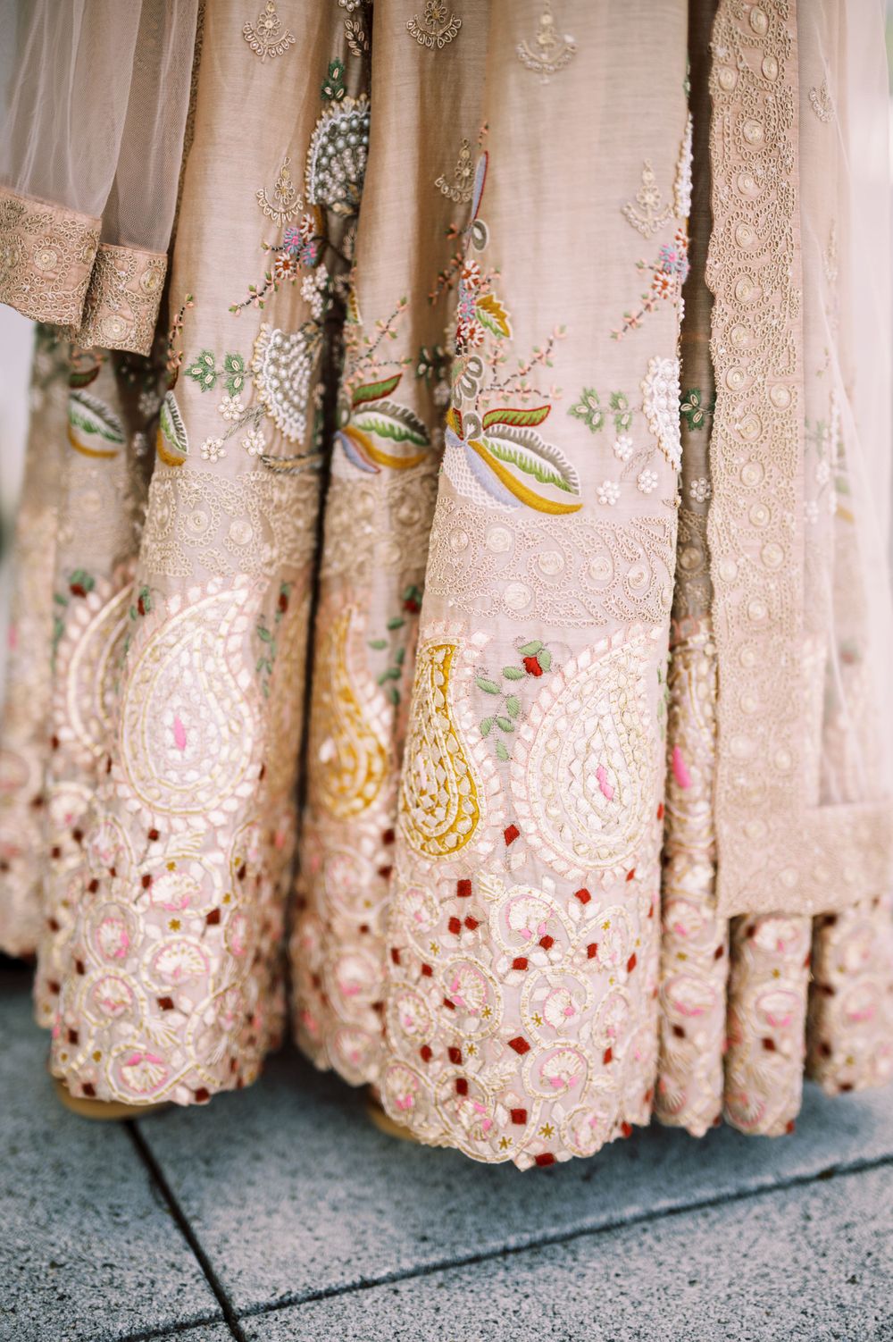 Close-up detail of blush pink saree fabric with intricate embroidery featuring floral patterns and delicate beadwork.
