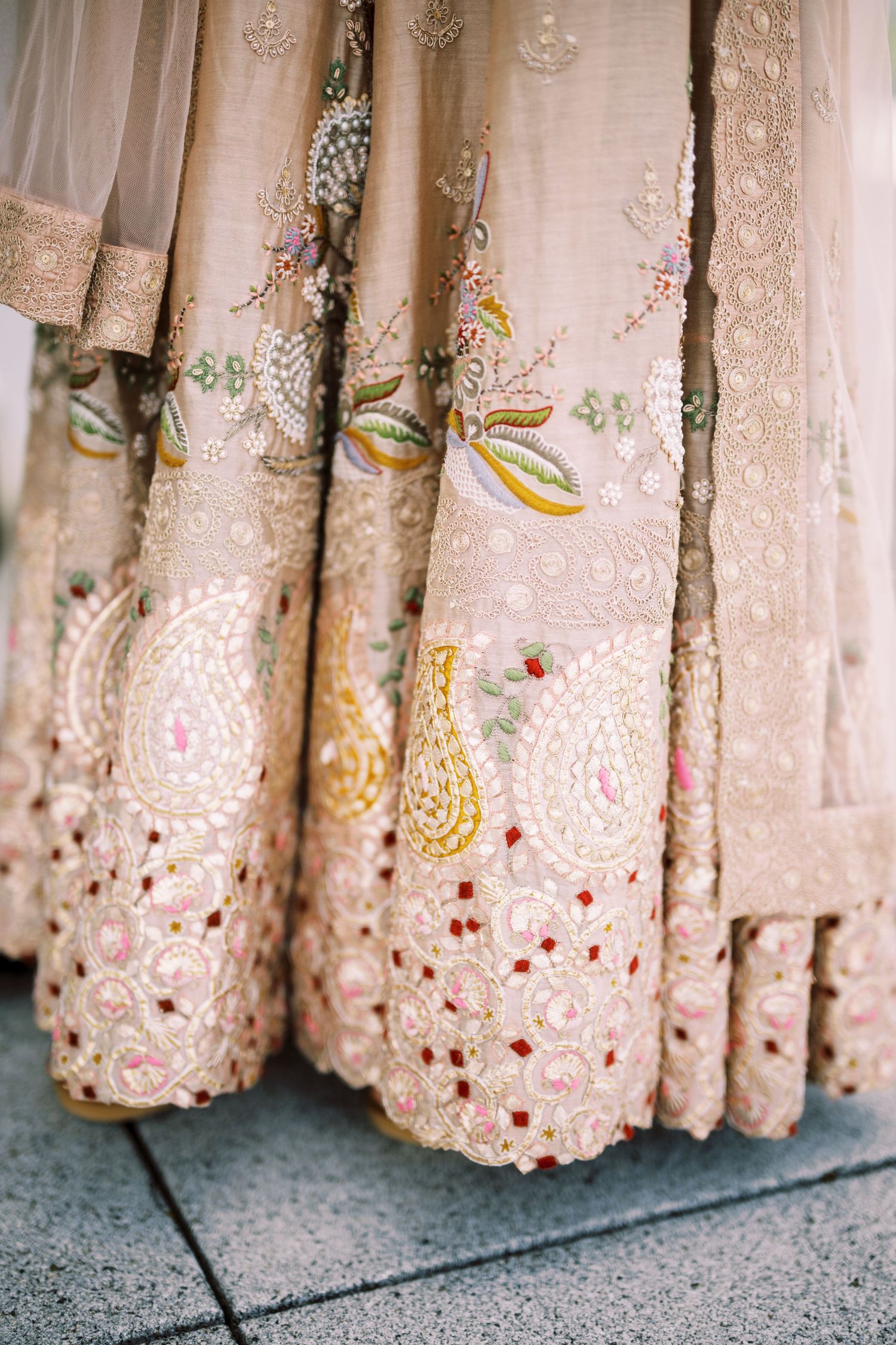 Close-up detail of blush pink saree fabric with intricate embroidery featuring floral patterns and delicate beadwork.