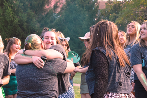 Friends sharing hugs and embraces during an outdoor celebration.