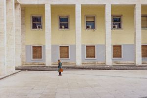 Minimalist white building facade with symmetrical windows and columns. Tirana, Albania,