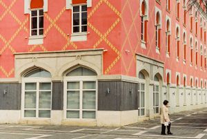 Pink building with decorative diamond patterns and arched windows on a quiet street corner. Tirana, Albania,