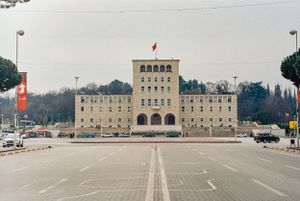 Imposing government building with classical architecture and empty parking lot in foreground. Tirana, Albania,