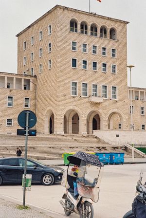 A vibrant street scene in Tirana, Albania, featuring colorful buildings, Skanderbeg Square, and the Et'hem Bey Mosque.