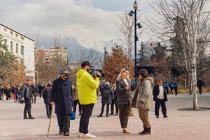 City square filled with people gathering against mountain backdrop. Tirana, Albania,
