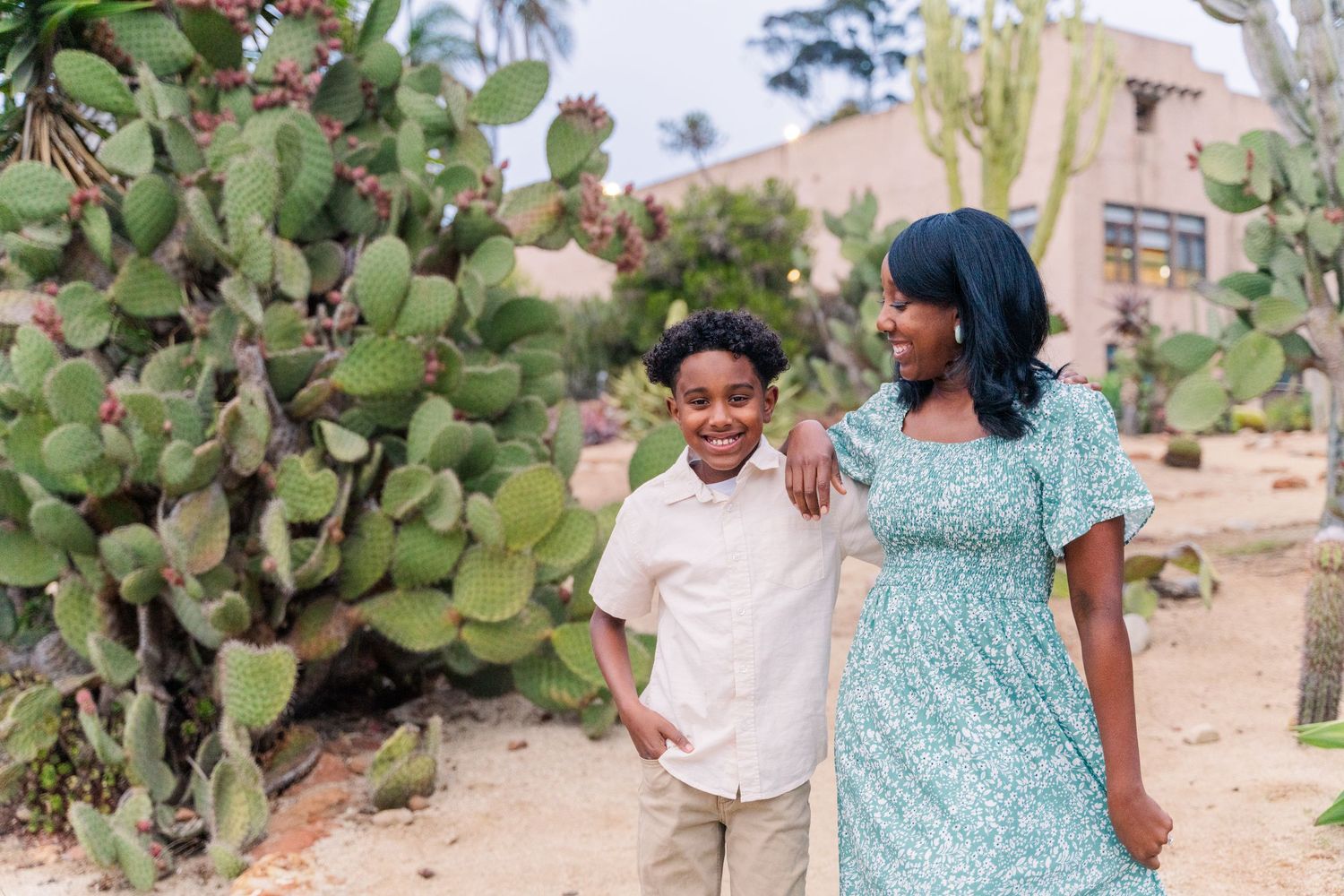 Sweet mother and son moment captured in front of desert cactus garden wearing casual summer outfits.