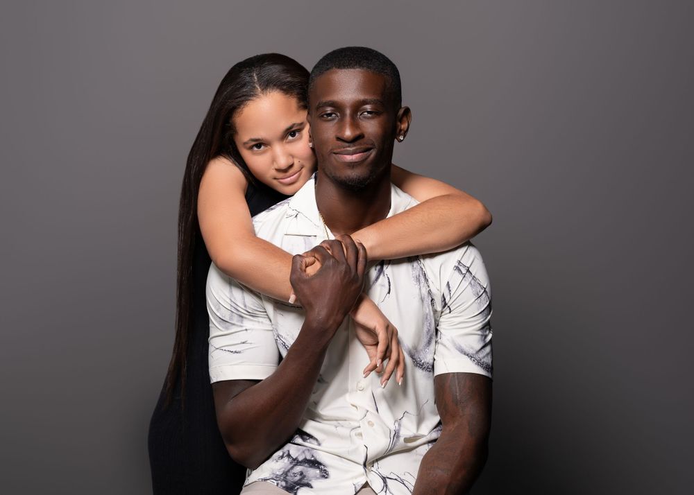 Loving couple embracing in casual white outfits during a studio photoshoot.