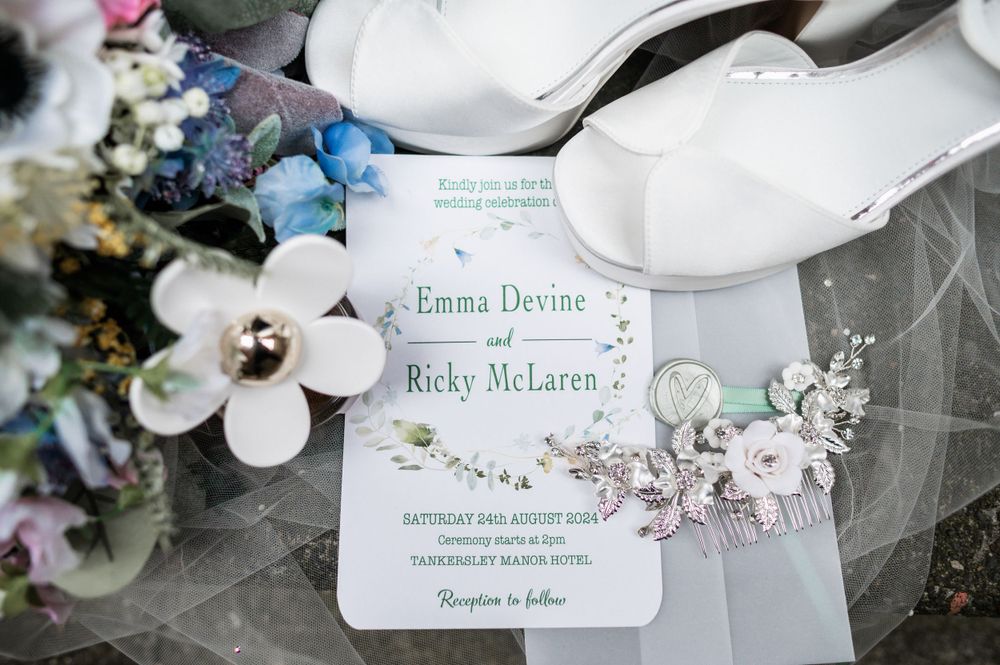 Floral wedding invitation with white shoes and delicate flower details.