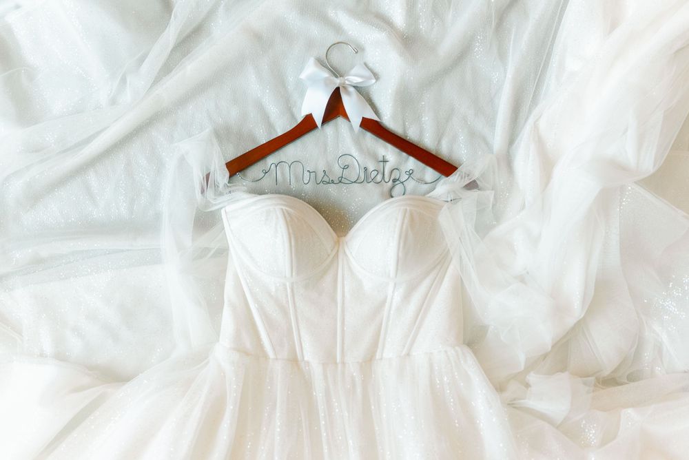 White wedding dress hanging on display against soft fabric background.