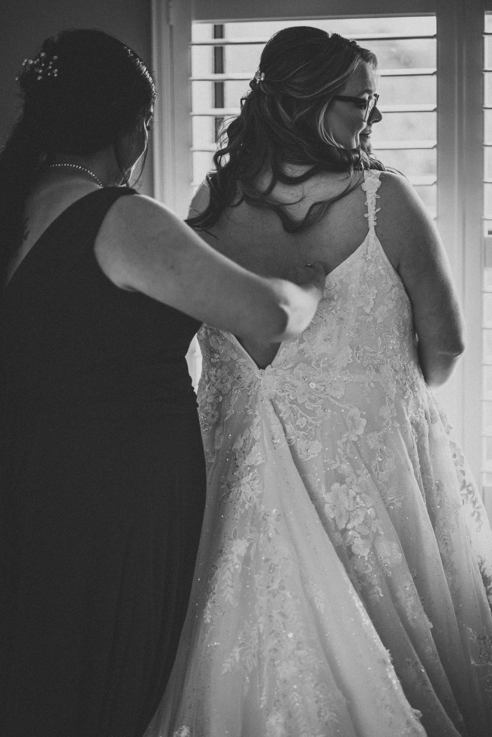 Black and white photo of final wedding dress adjustments being made.