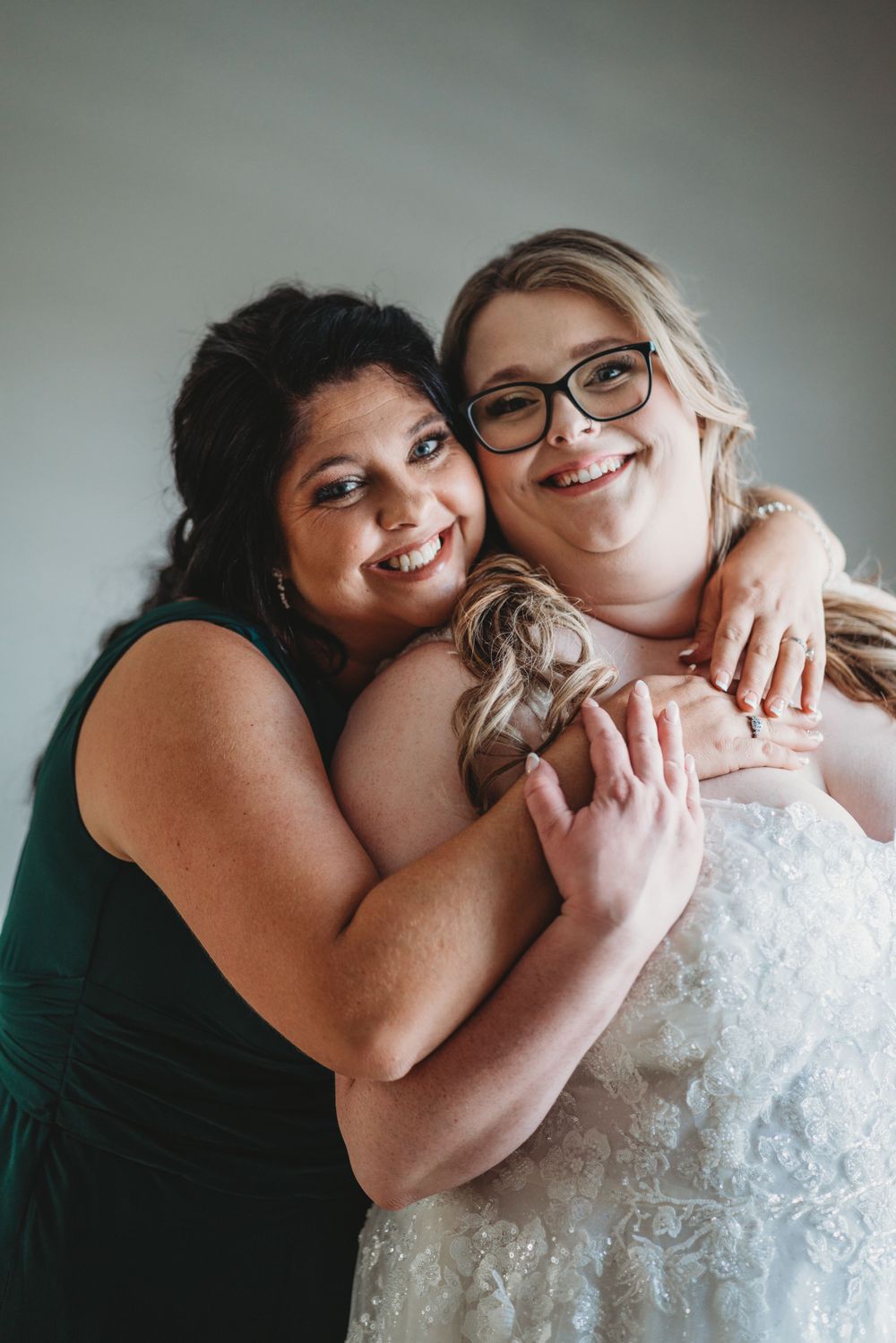 Candid emotional moment between bride and friend embracing.
