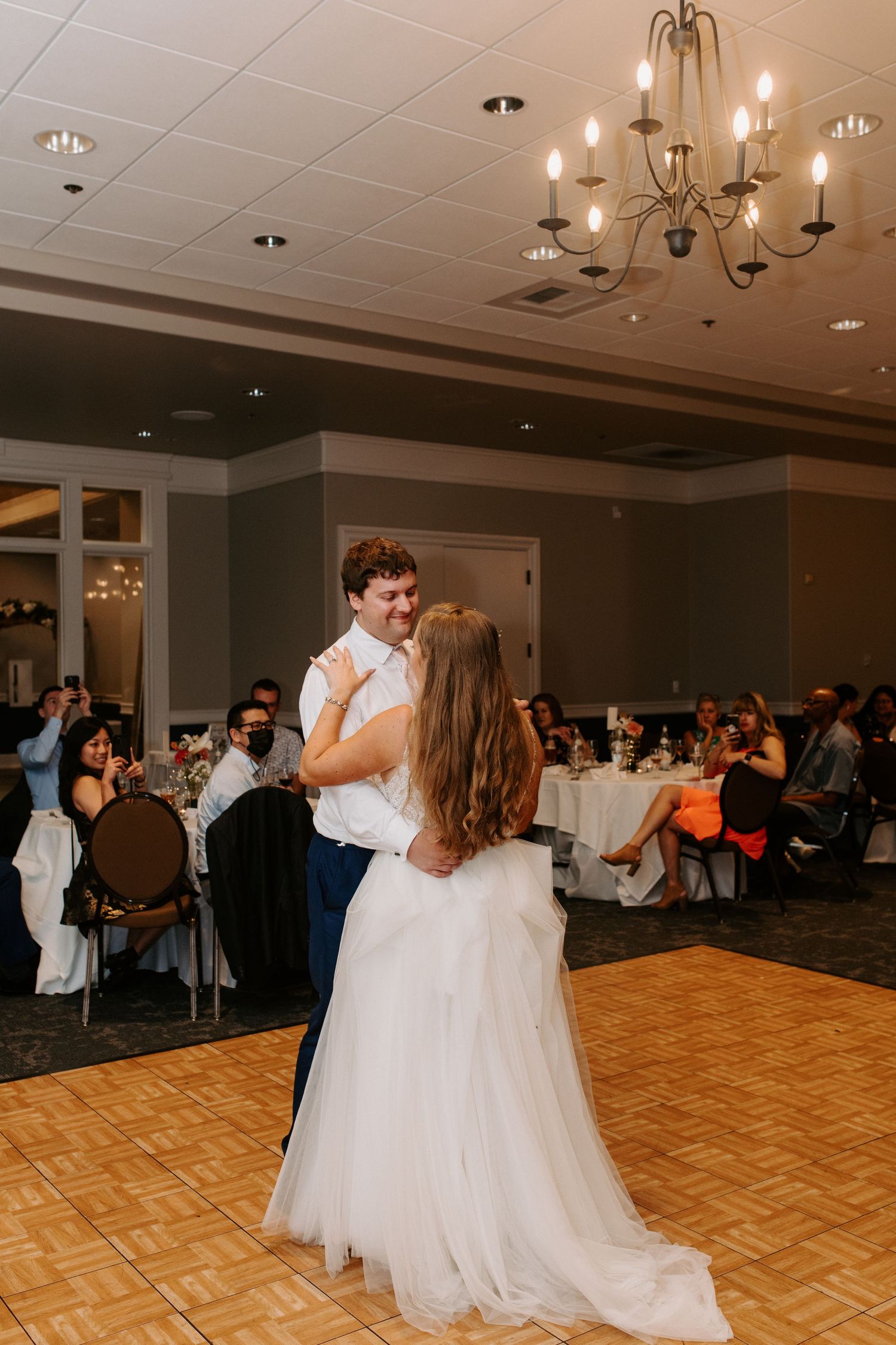 Wedding reception dance floor scene with couples dancing in an elegant ballroom setting.
