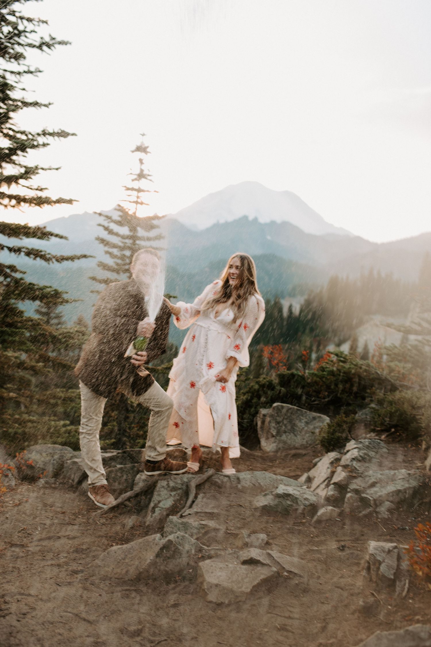 Dancing in flowy dresses against mountain backdrop at sunset.