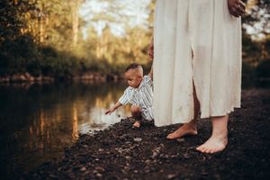 Close-up shots of family members' feet and legs standing in shallow river water.