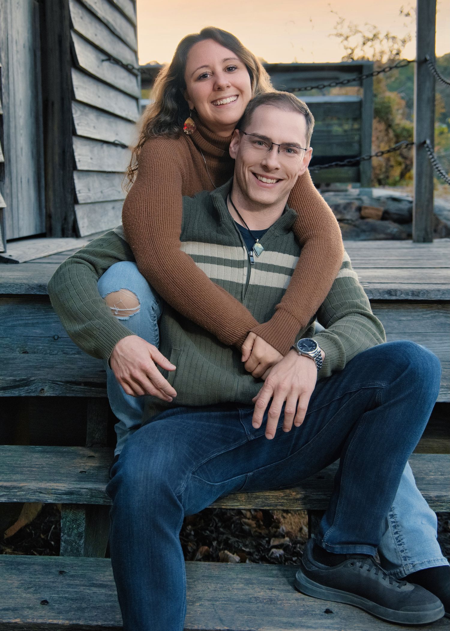 A couple sharing a tender moment sitting on wooden steps outdoors.
