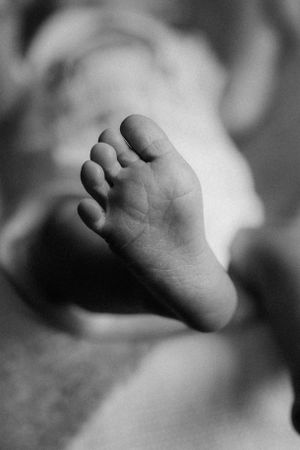 Close-up black and white photograph of tiny baby foot in soft focus showing delicate toes.