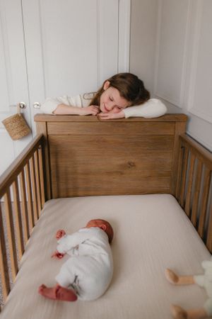 Sibling looking at newborn in crib for in home newborn session captured by newborn Maryland photographer Mallory Bramlett.