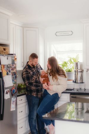 A couple shares an intimate moment while spending time together in their bright modern kitchen.