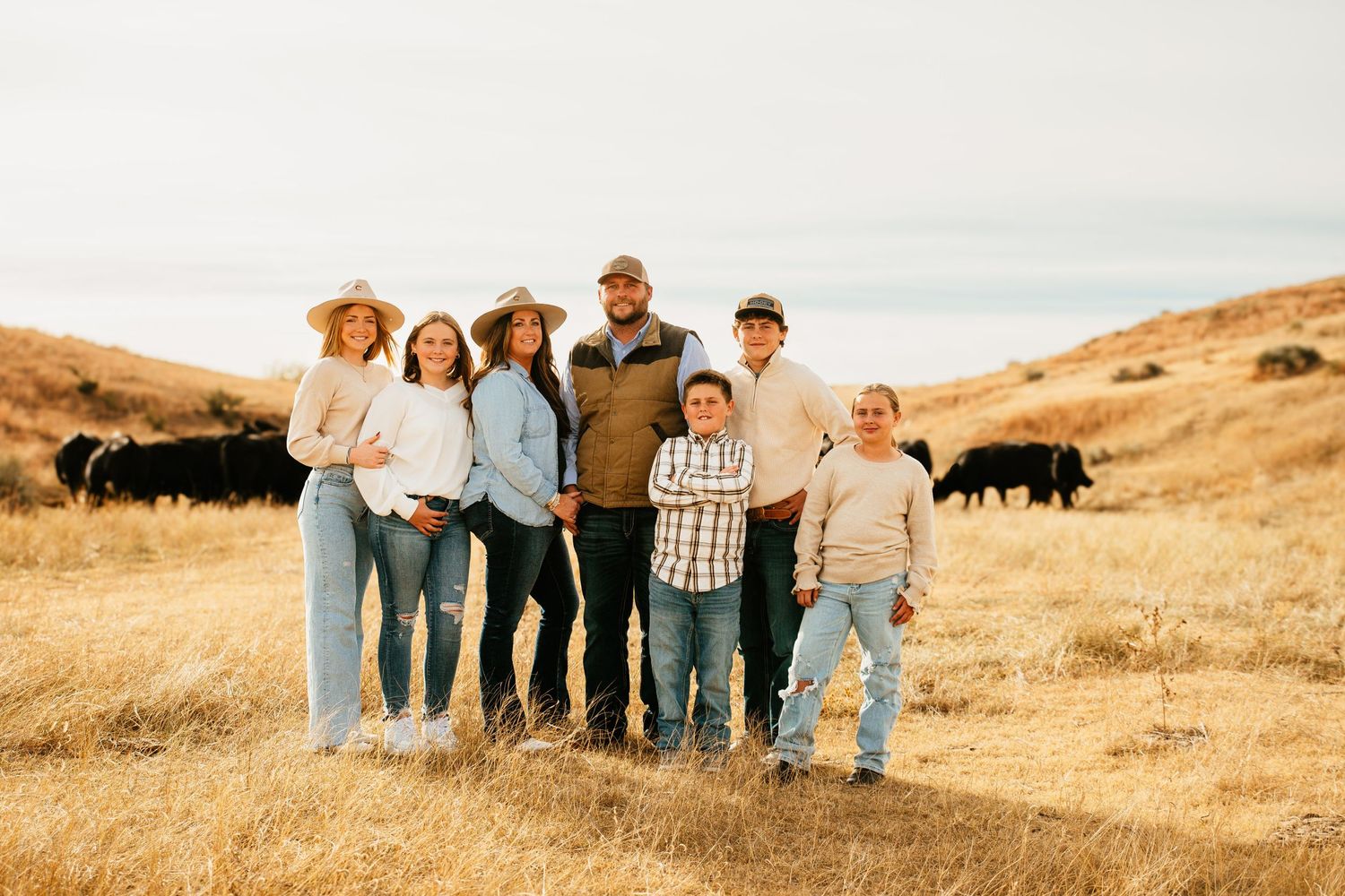 Group posing together on hillside with grazing buffalo in background.