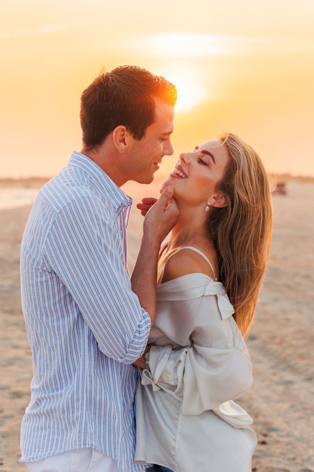 Romantic couple sharing an intimate moment at sunset on the beach with golden light in the background.