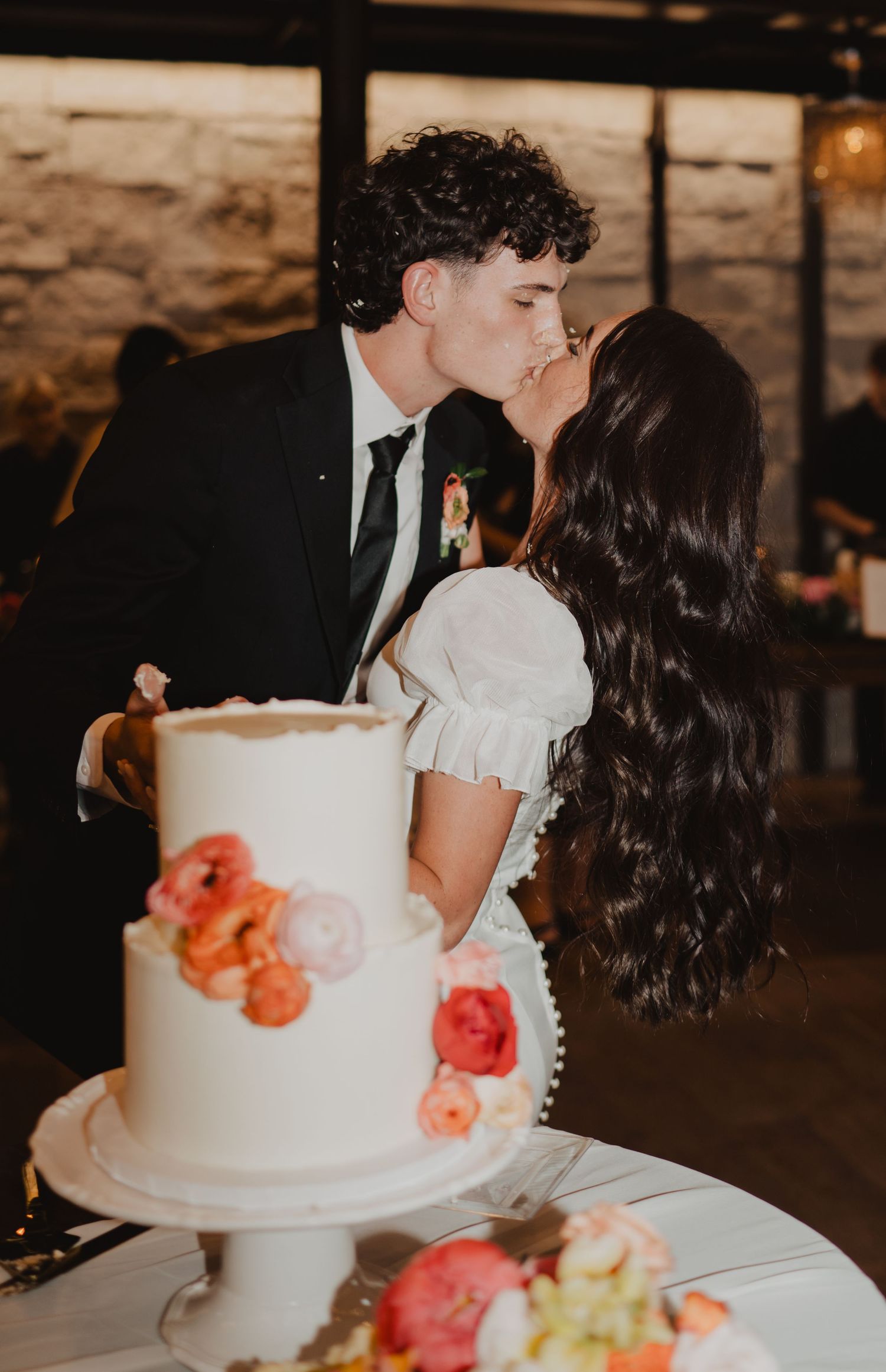 Romantic moment between newlyweds cutting their floral-decorated wedding cake.
