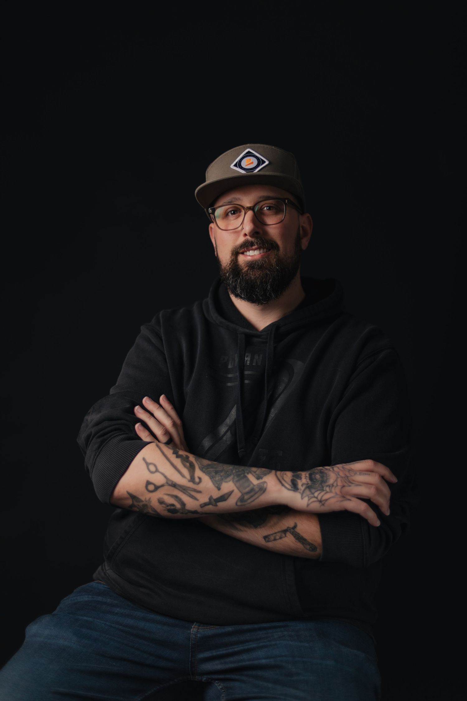 Professional portrait series showing dramatic lighting on person in black shirt with glasses and facial hair against dark background.