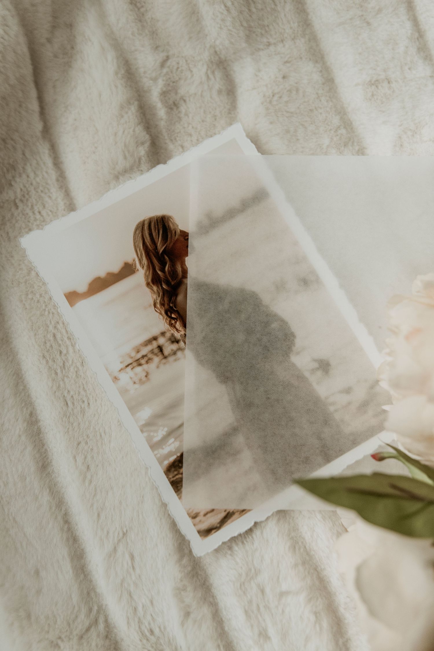 Vintage sepia photograph laying on white textured fabric with a green leaf accent.