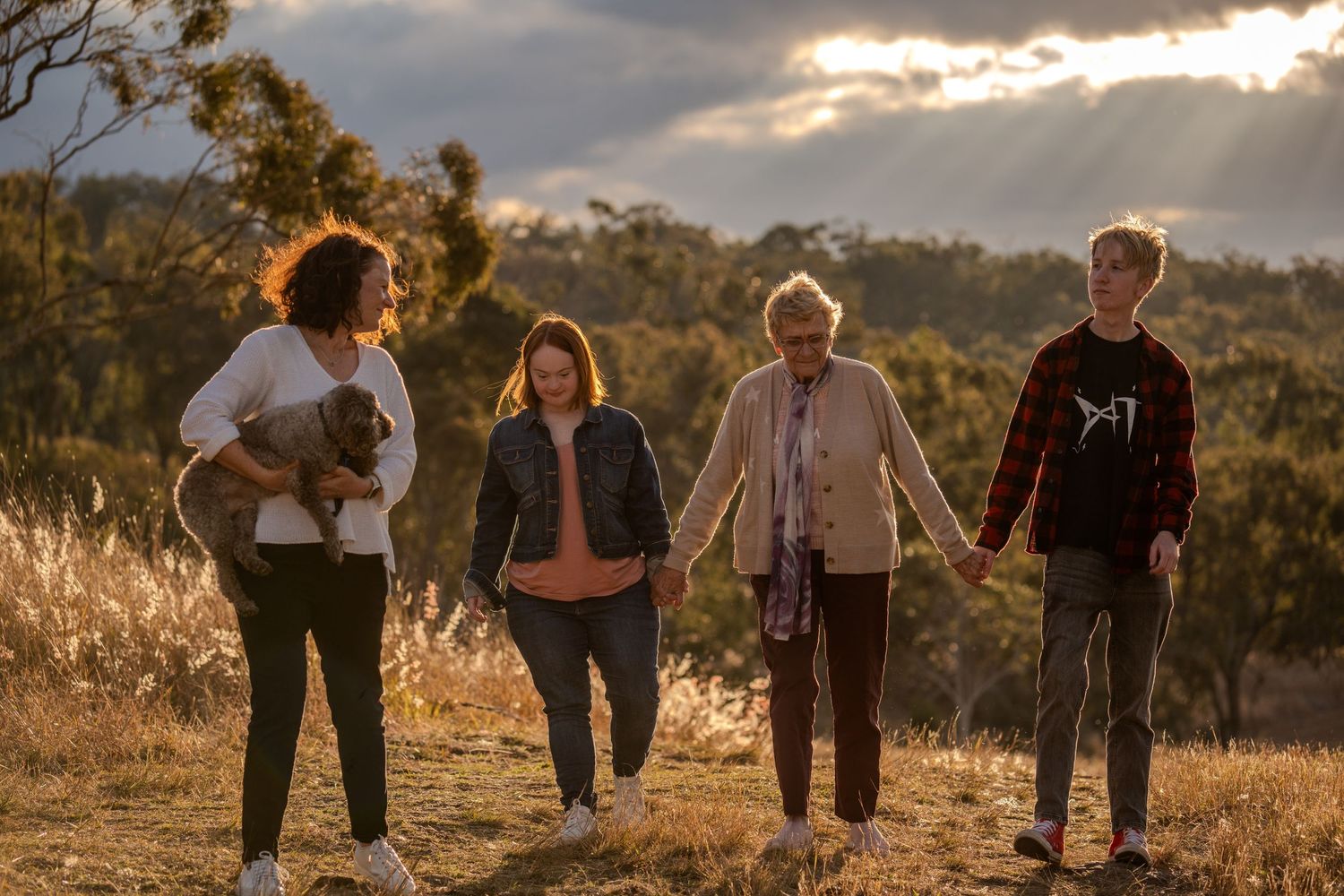 Group of hikers walking together on a hilltop trail during golden hour sunset.