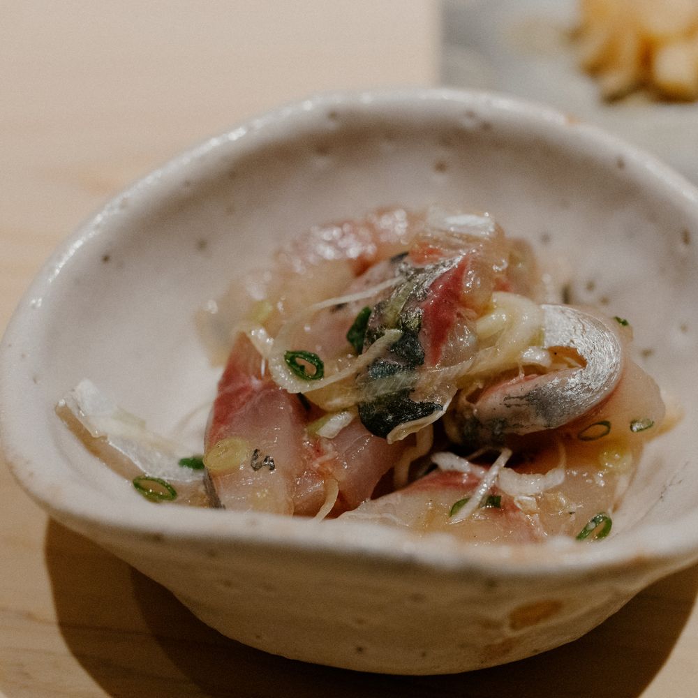 Marinated fish with herbs and garnishes served in a rustic ceramic bowl.