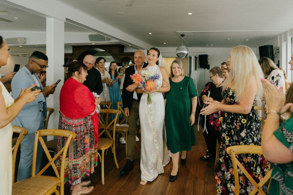Wedding guests standing and applauding during reception celebration.