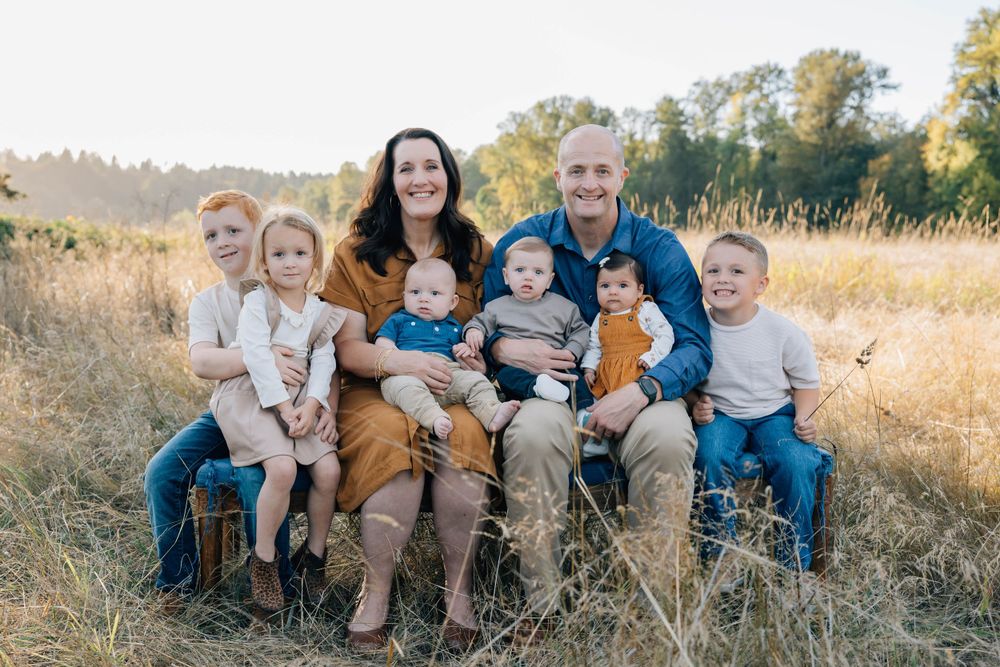 Happy family of eight posing together in a beautiful golden autumn field.