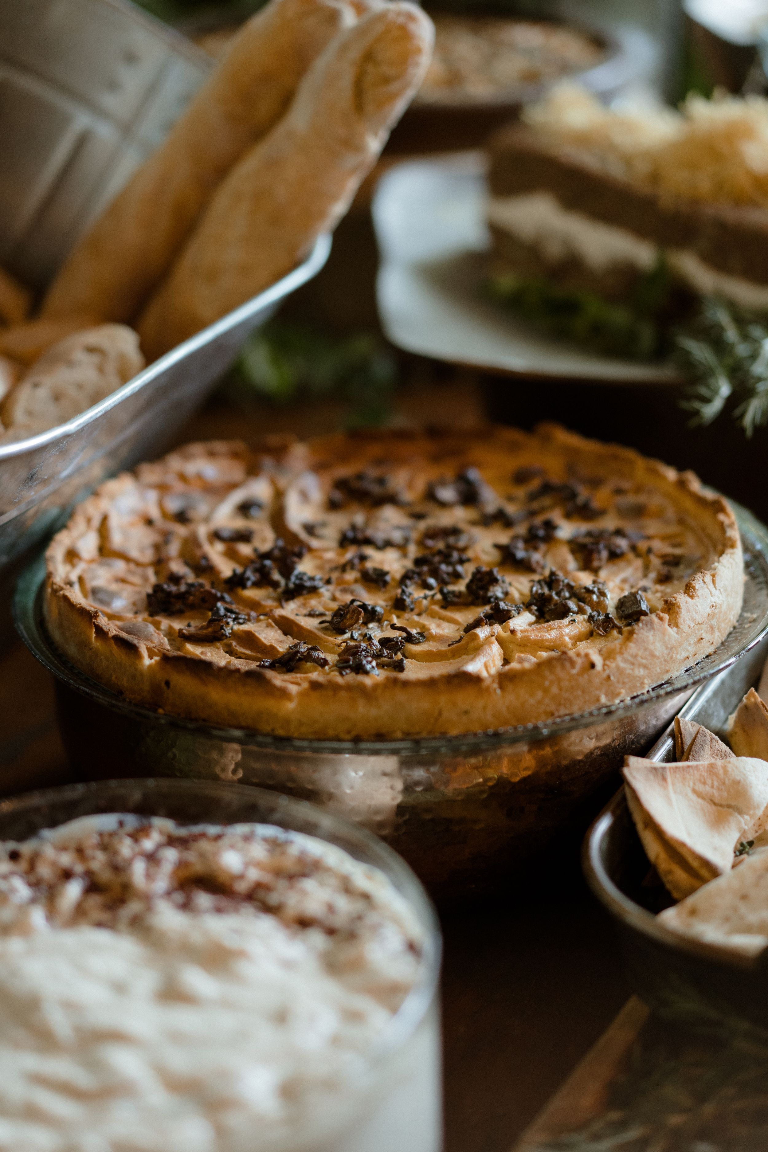 Close-up of homemade pies with whipped cream and dark toppings on wooden serving boards.