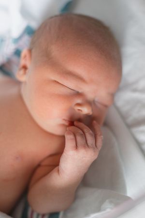 A sleeping baby's face shown in a sequence of five close-up photos against white bedding.