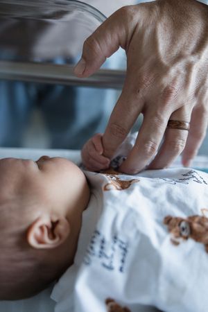 A medical professional performs a gentle examination of a baby's ear using an otoscope instrument.