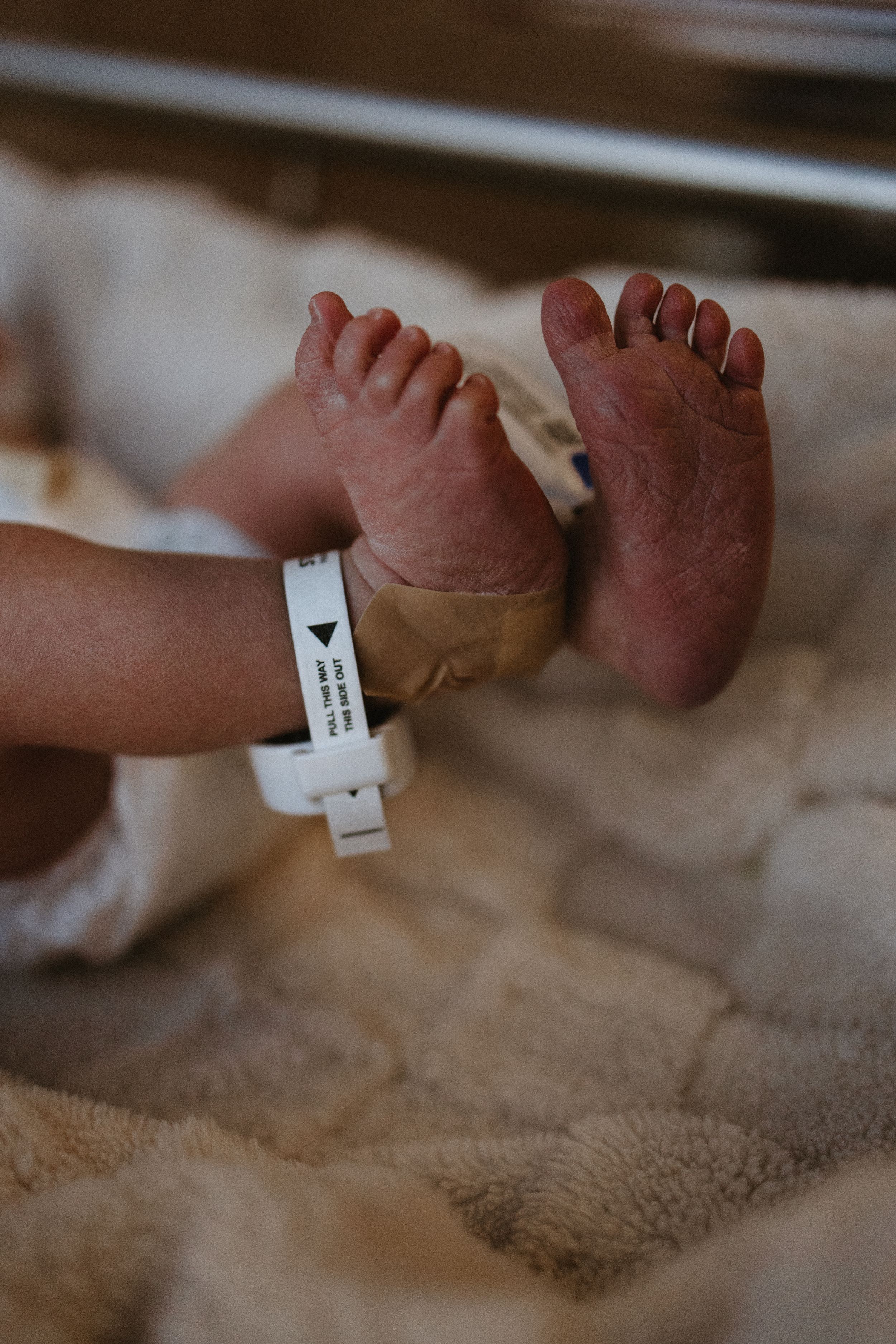 Close-up of newborn baby feet with hospital identification bracelet.