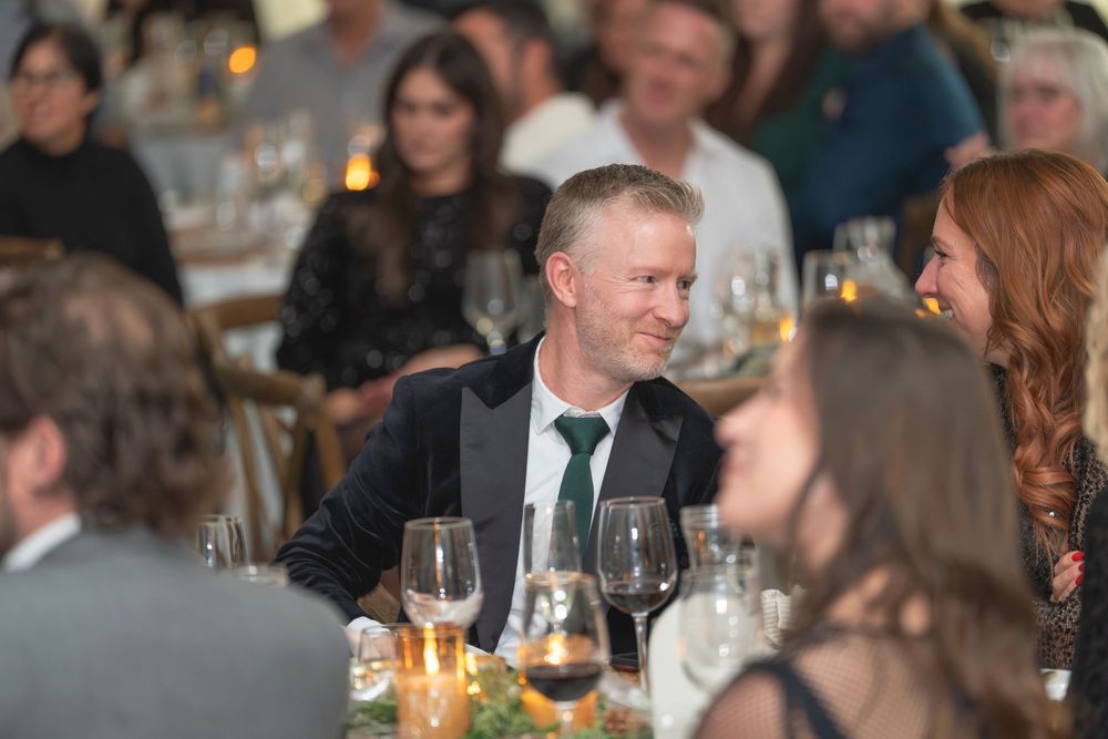 People gathered around a table at an elegant dinner party with wine glasses and candlelight creating an intimate atmosphere.