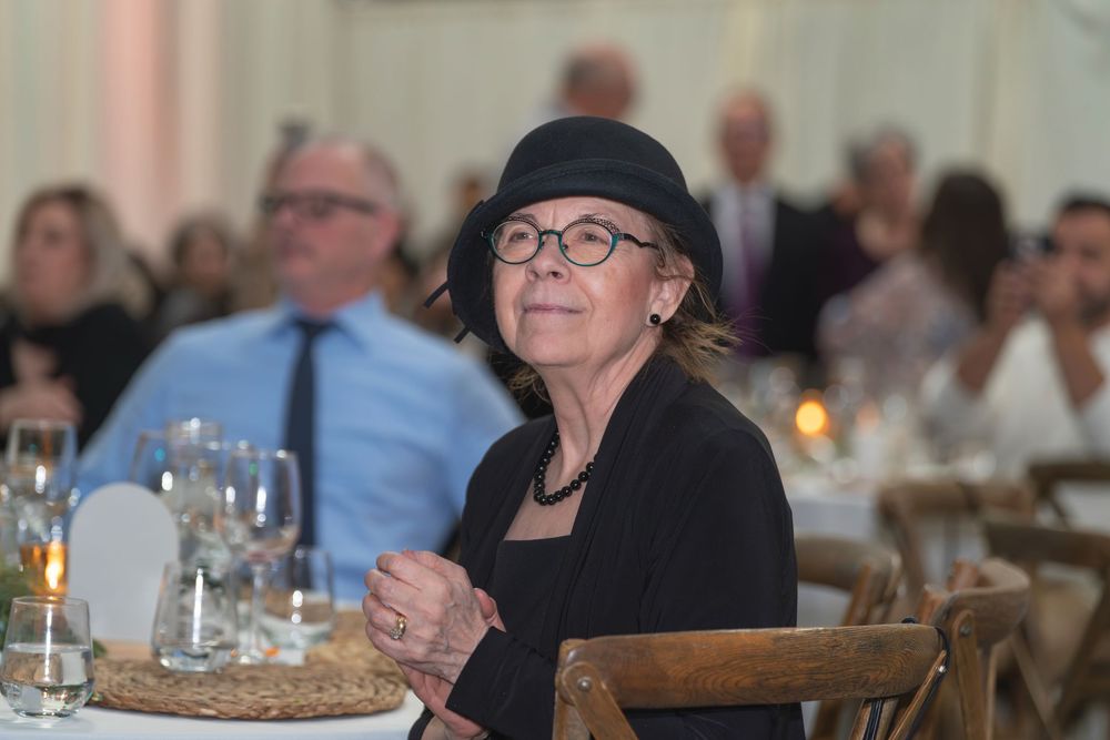People gathered at tables for a formal dining event in an elegant banquet setting.