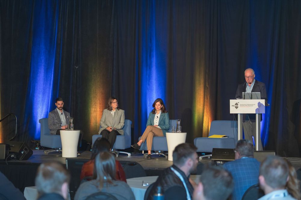 Business conference stage setup with panel discussion and blue accent lighting.